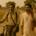Two Indian brothers walk on a dusty village road, one with a bicycle, the other with a red gamcha, as village children wave in the background