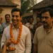 Villagers celebrate Mahesh’s government job success with sweets and garlands while Rameshwar forces a bitter smile.