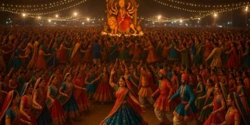 Thousands of dancers in colorful traditional attire performing Garba at night under festive lights, with Goddess Durga’s idol in the background.